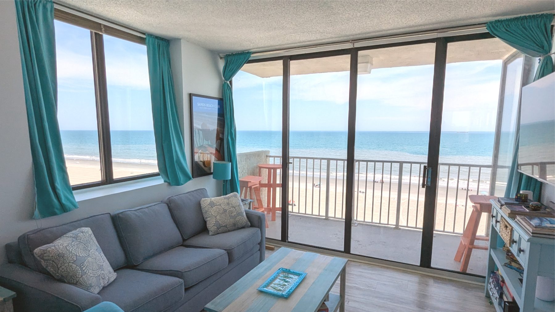Corner window and oceanfront balcony sliding glass doors opening the living space to the outside at 728 Sands Beach Club